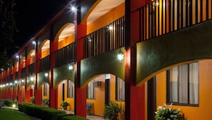 A hotel with multiple balconies, outdoor seating, and potted plants.