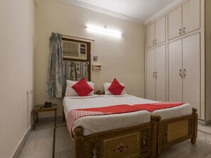 A bedroom with a wooden bed, a nightstand, a wardrobe, and a window with curtains. - OYO 1074 Apartment Banjara Hills (Hyderabad)