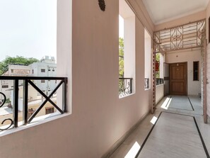 A corridor with a balcony, a wooden door, and a view of neighboring buildings. - OYO 1074 Apartment Banjara Hills (Hyderabad)