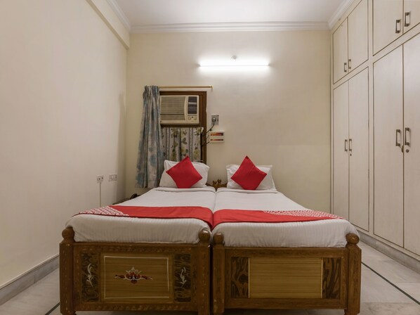 A double bed with a red and white bedspread, two red pillows, and a wooden headboard with intricate carvings. - OYO 1074 Apartment Banjara Hills (Hyderabad)