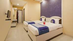 A hotel room with two beds, a ceiling fan, a TV, and a bathroom visible through an open door. - OYO Rooms Banjara Hills Road No 1 (Hyderabad)