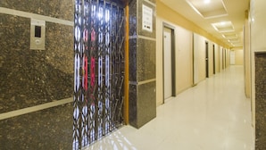 A hallway with a marble wall, an elevator, and a sign indicating floor numbers. - OYO Rooms Banjara Hills Road No 1 (Hyderabad)