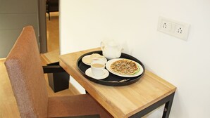 A small dining table with a tray containing a teapot, cups, and a plate of food. - OYO Rooms Banjara Hills Road No 1 (Hyderabad)