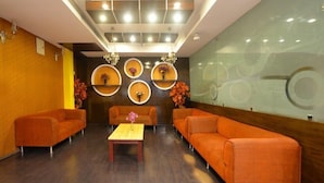 A modern lobby with orange sofas, a wooden coffee table, and decorative wall shelves. - OYO Rooms Banjara Hills Road No 1 (Hyderabad)