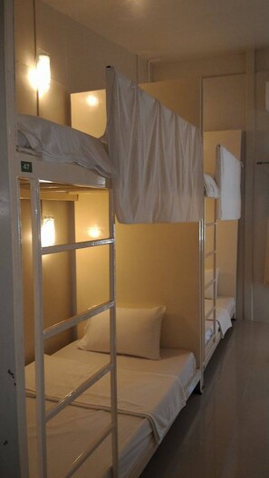 A bunk bed room with a ladder, a pillow, and a wall-mounted light. - The Best Hostel (Koh Tao)