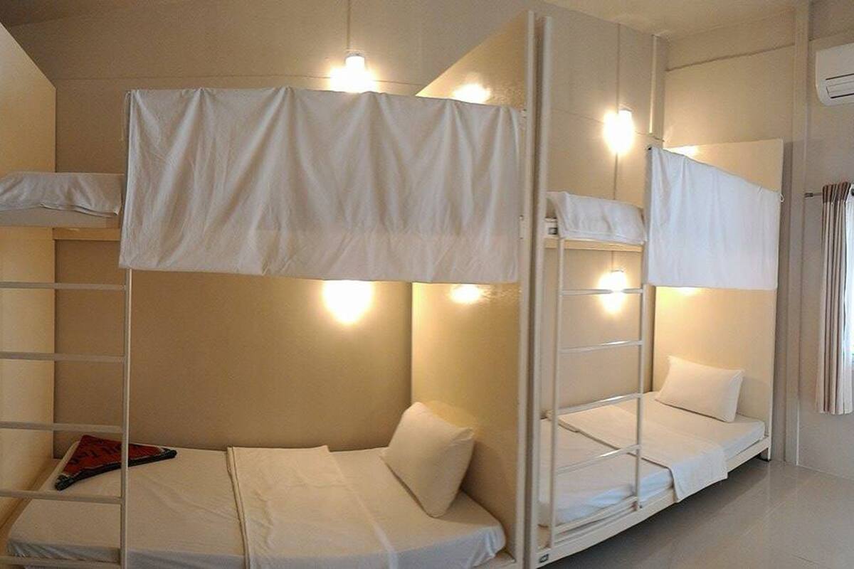 A bunk bed room with white bedding and overhead lighting.