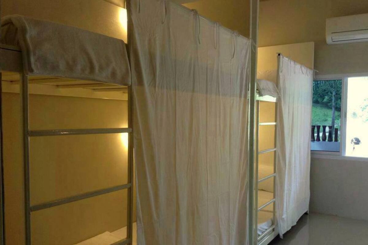 A room with bunk beds, a window with curtains, and an air conditioning unit.