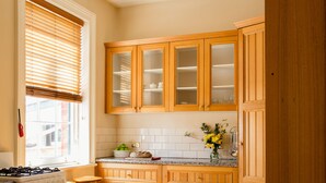 Una cocina con armarios de madera, encimera de granito, estufa y ventana con persianas.