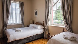 Un dormitorio con una cama grande, dos mesitas de noche, una ventana con cortinas y vistas al exterior.