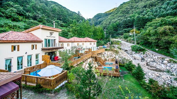 A hillside hotel with a pool, wooden deck, and mountain views.