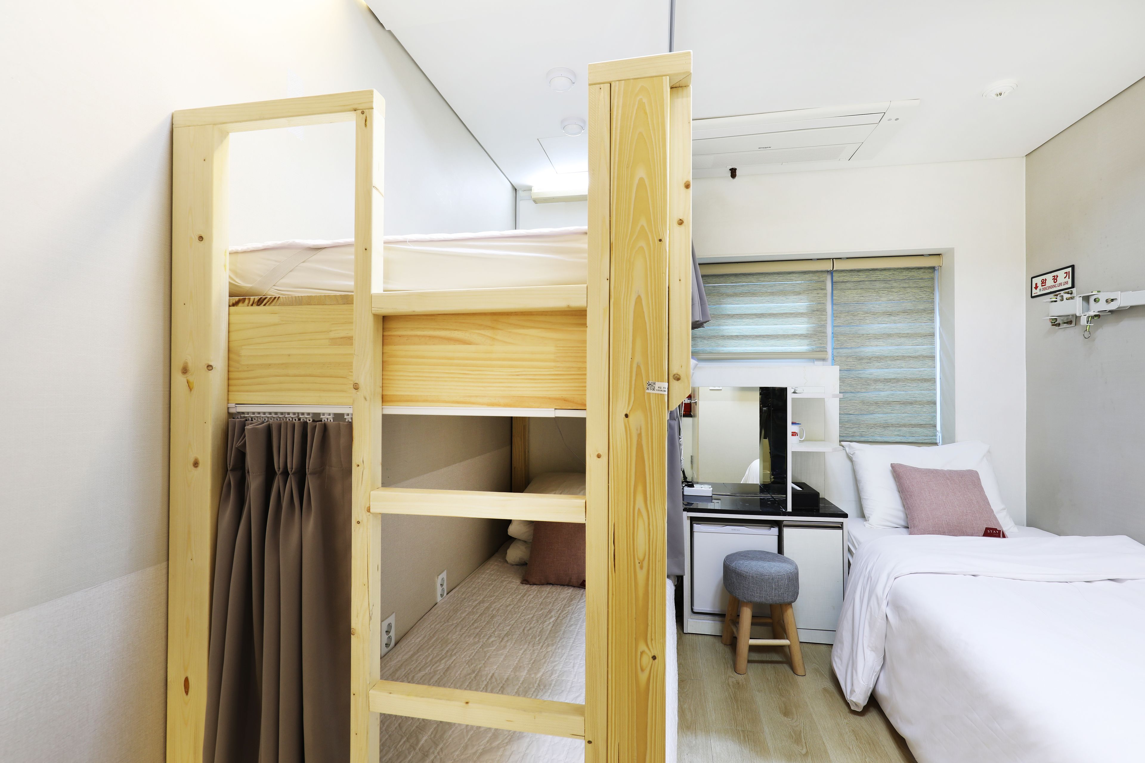 A compact room with a bunk bed, a desk, and a small stool.