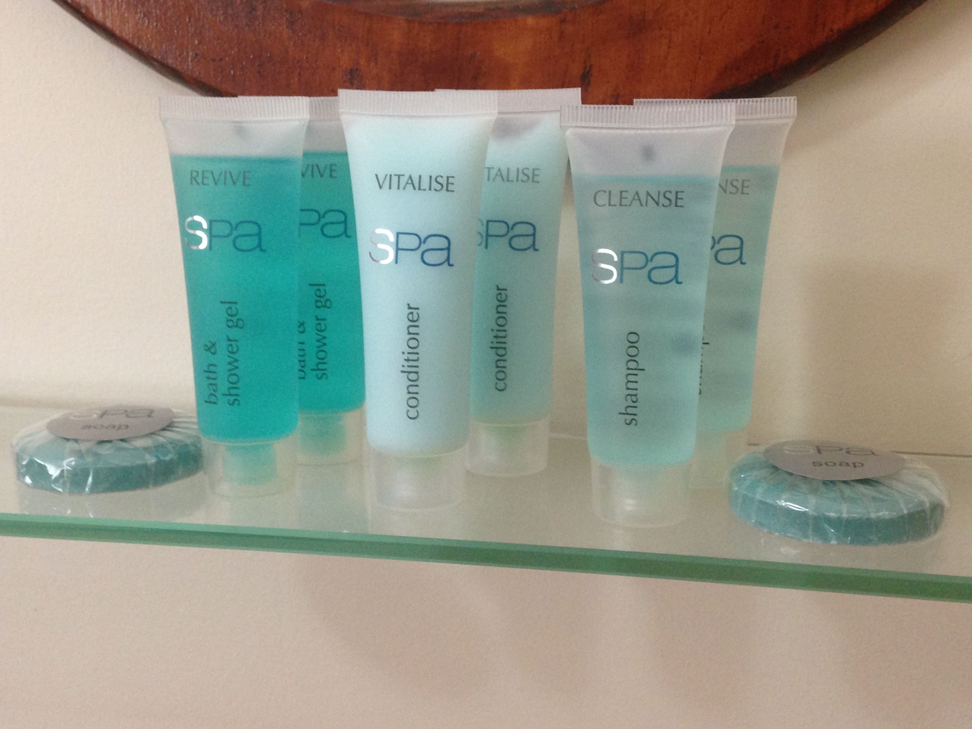 A shelf with various spa products including bath & shower gel, conditioner, and shampoo.