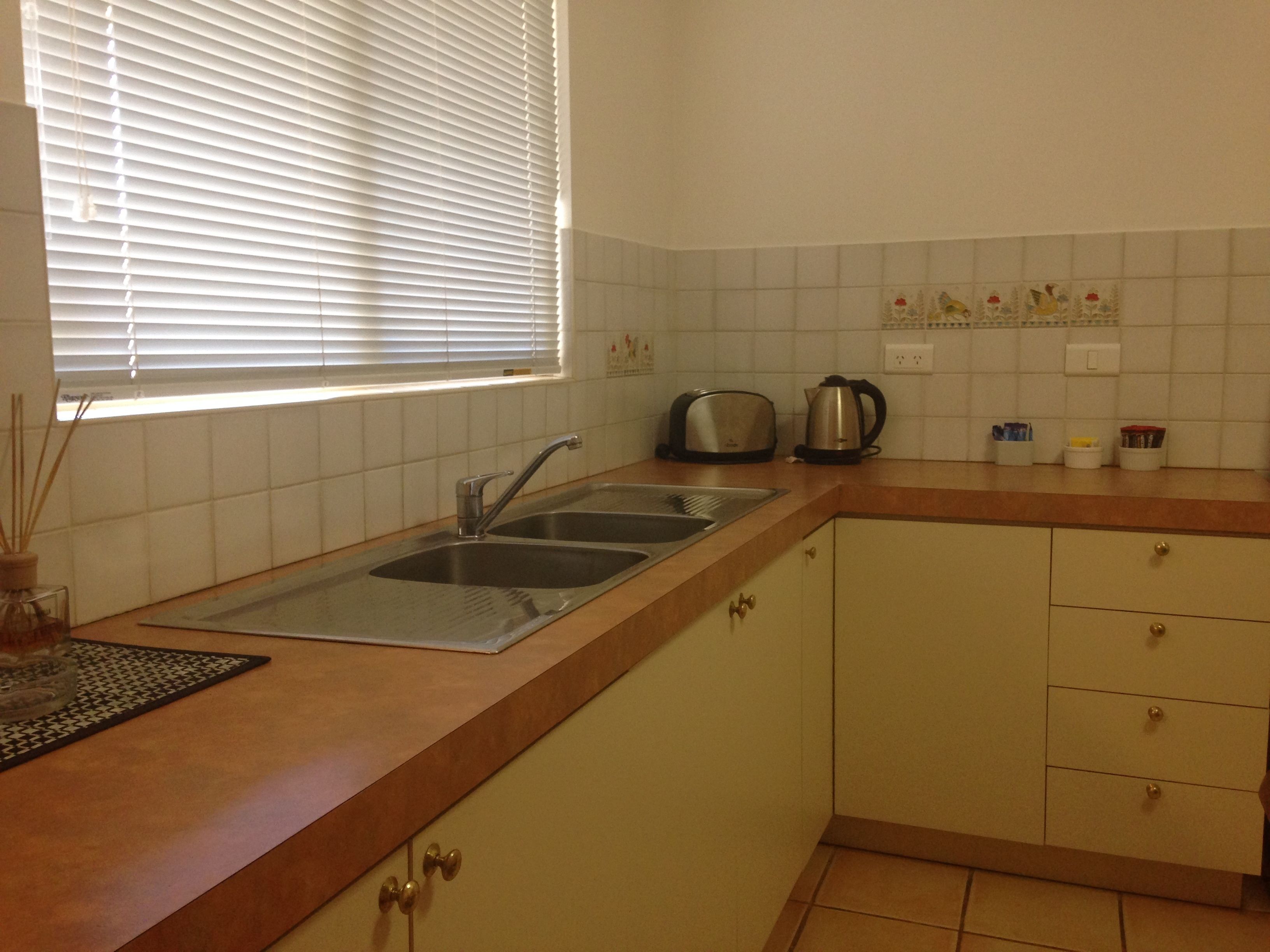 A kitchen with a double sink, a toaster, and a kettle.