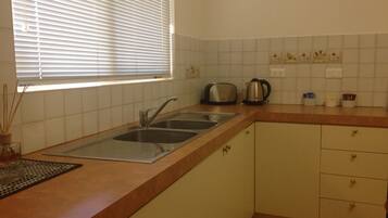A kitchen with a double sink, a toaster, and a kettle.