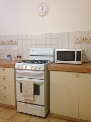 A kitchen with a stove, microwave, and a clock on the wall. - The Nosh & Nod - Avon Terrace (York)