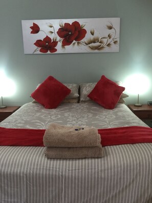 A neatly made bed with striped bedding, two red pillows, and a beige towel. - The Nosh & Nod - Avon Terrace (York)