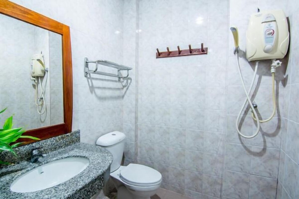 Une salle de bain équipée d’un lavabo en granit, de toilettes, d’un porte-serviettes et d’une douchette à main.