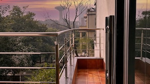 A balcony with a view of a sunset, a tiled floor, and a metal railing. - YUHI MANSIONS | A Boutique Stay (Gurugram)