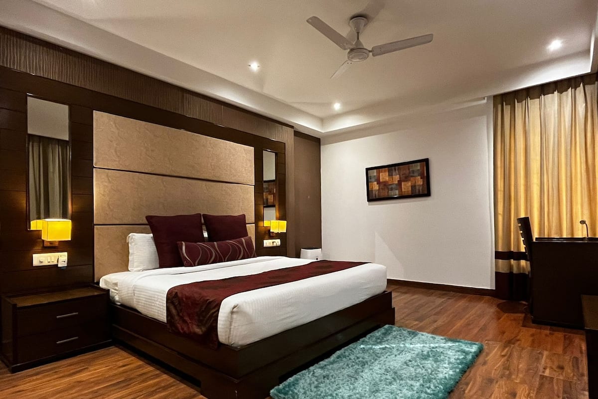 Ein modernes Hotelzimmer mit einem großen Bett, Holzboden, Deckenventilator und einem kleinen Teppich.