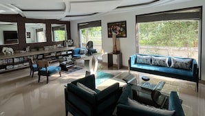 A spacious living room with a modern design, featuring a large sofa, a coffee table, and a fireplace. - YUHI MANSIONS | A Boutique Stay (Gurugram)