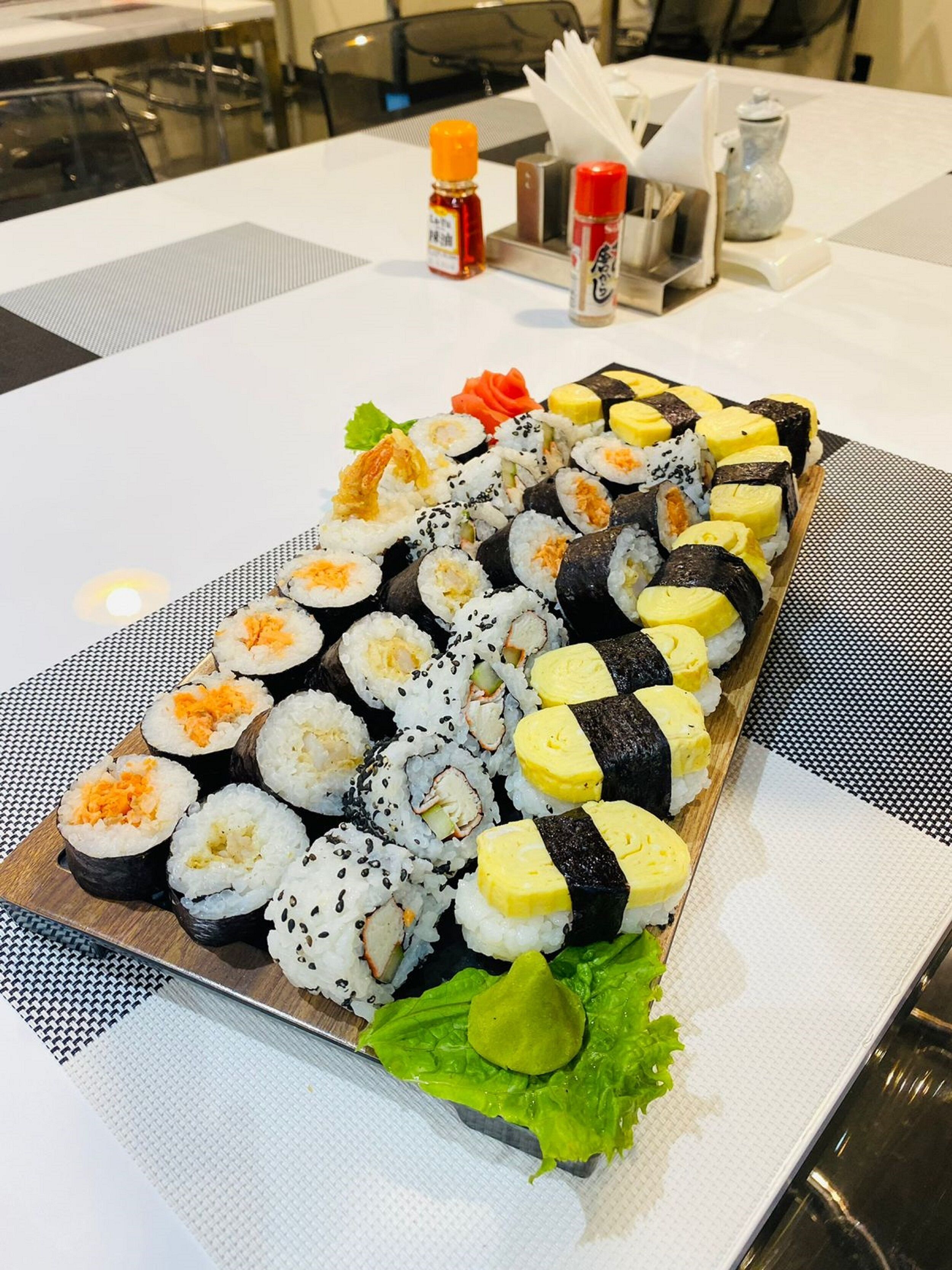 Un plateau de sushis variés est posé sur une table, sur laquelle se trouve un set de table.