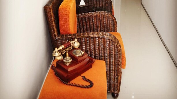 A hallway with wicker furniture and a vintage telephone. - Old Budget Hotel (George Town)