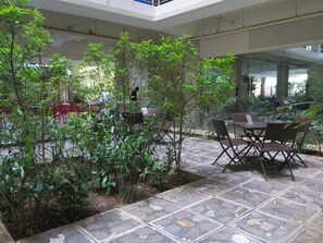 An indoor garden area with tables and chairs, surrounded by lush green plants. - Alicia Tower Residences - Adult Only - Hostel (Cebu City)