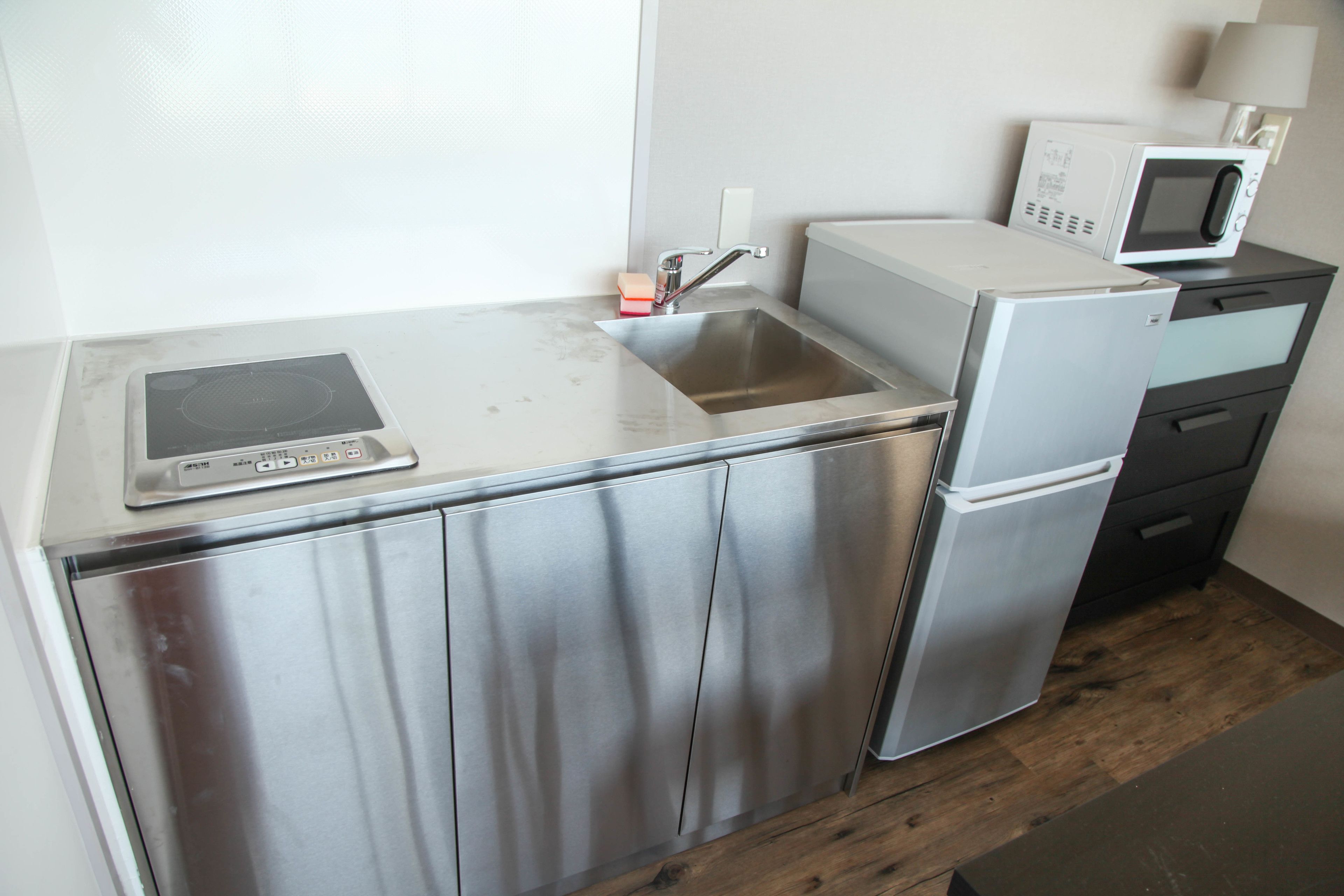 Una cocina compacta con un refrigerador de acero inoxidable, un microondas y un horno empotrado.