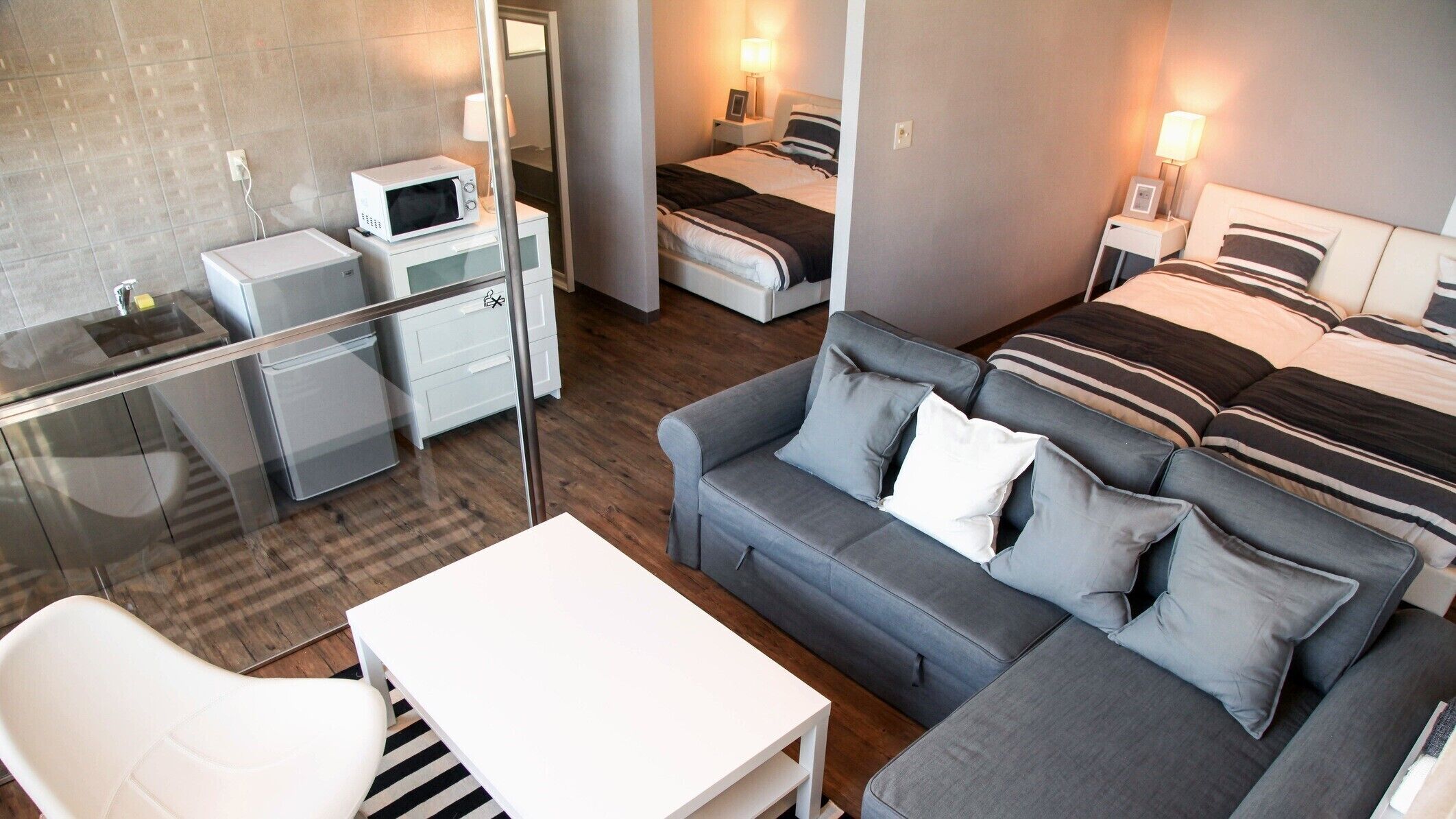 Ein modernes Hotelzimmer mit einer Glaskonstruktion, die den Wohnbereich von der Küchenzeile trennt.