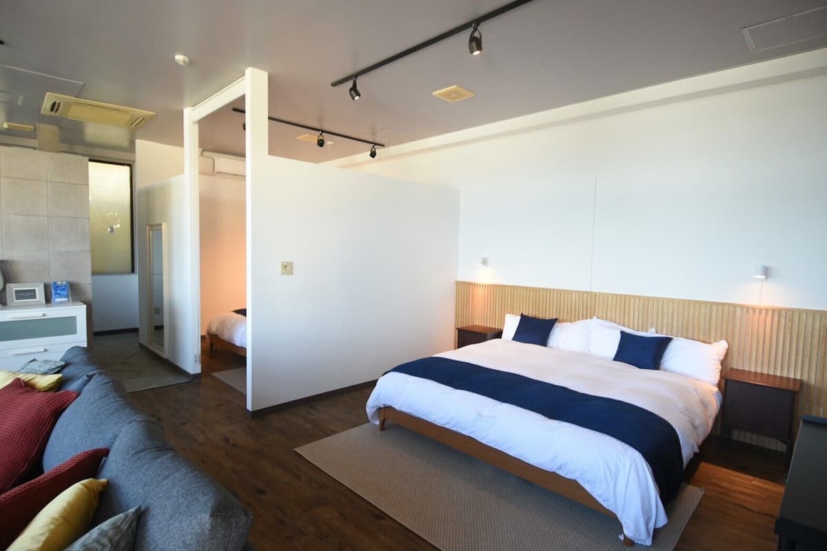 A modern hotel room with a large bed, a sofa, and a separate seating area.