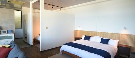 Una habitación de hotel moderna con una cama grande, un sofá y una zona de estar separada.