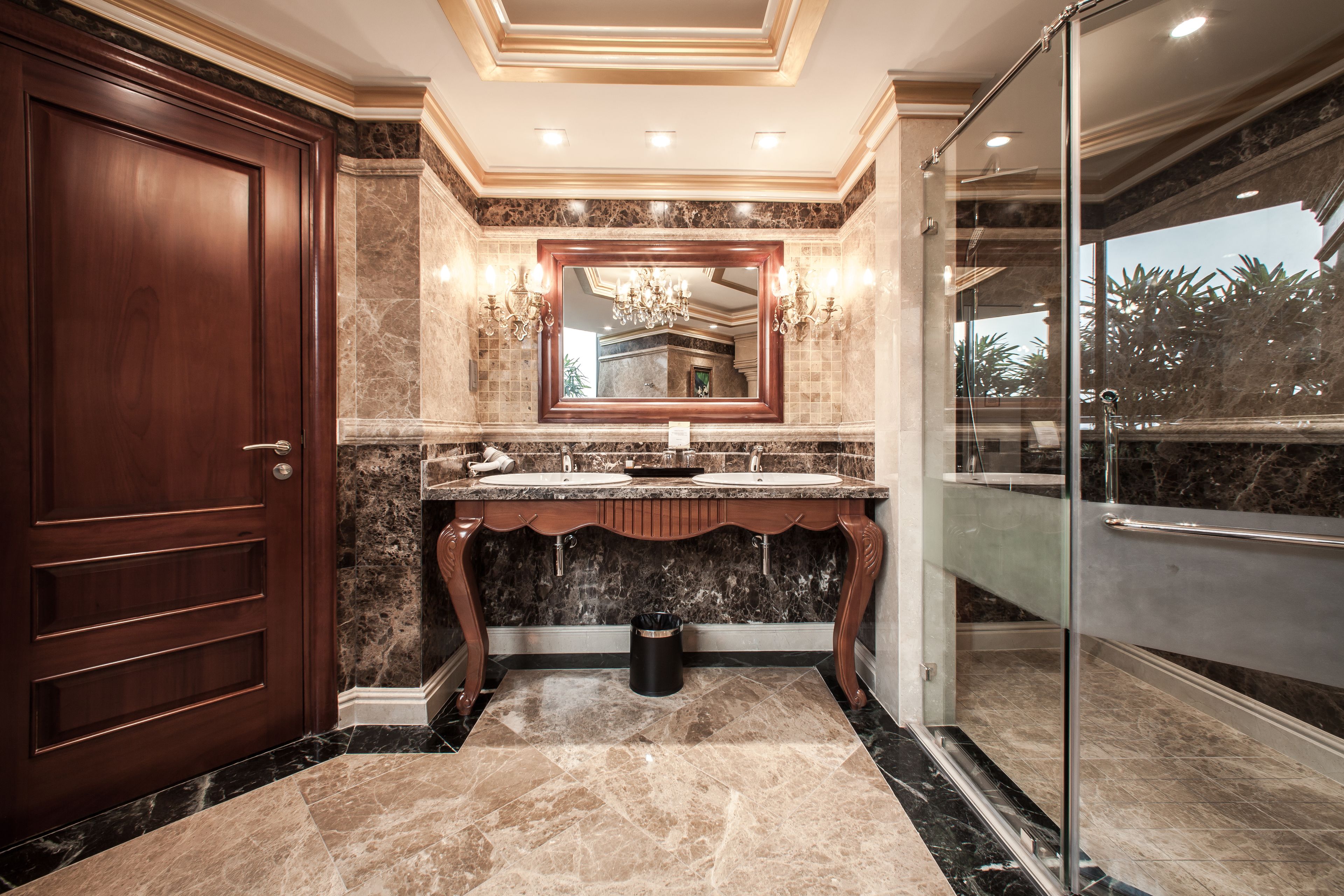 Un bagno di lusso con un mobile vanitario in marmo, uno specchio grande e una cabina doccia in vetro.