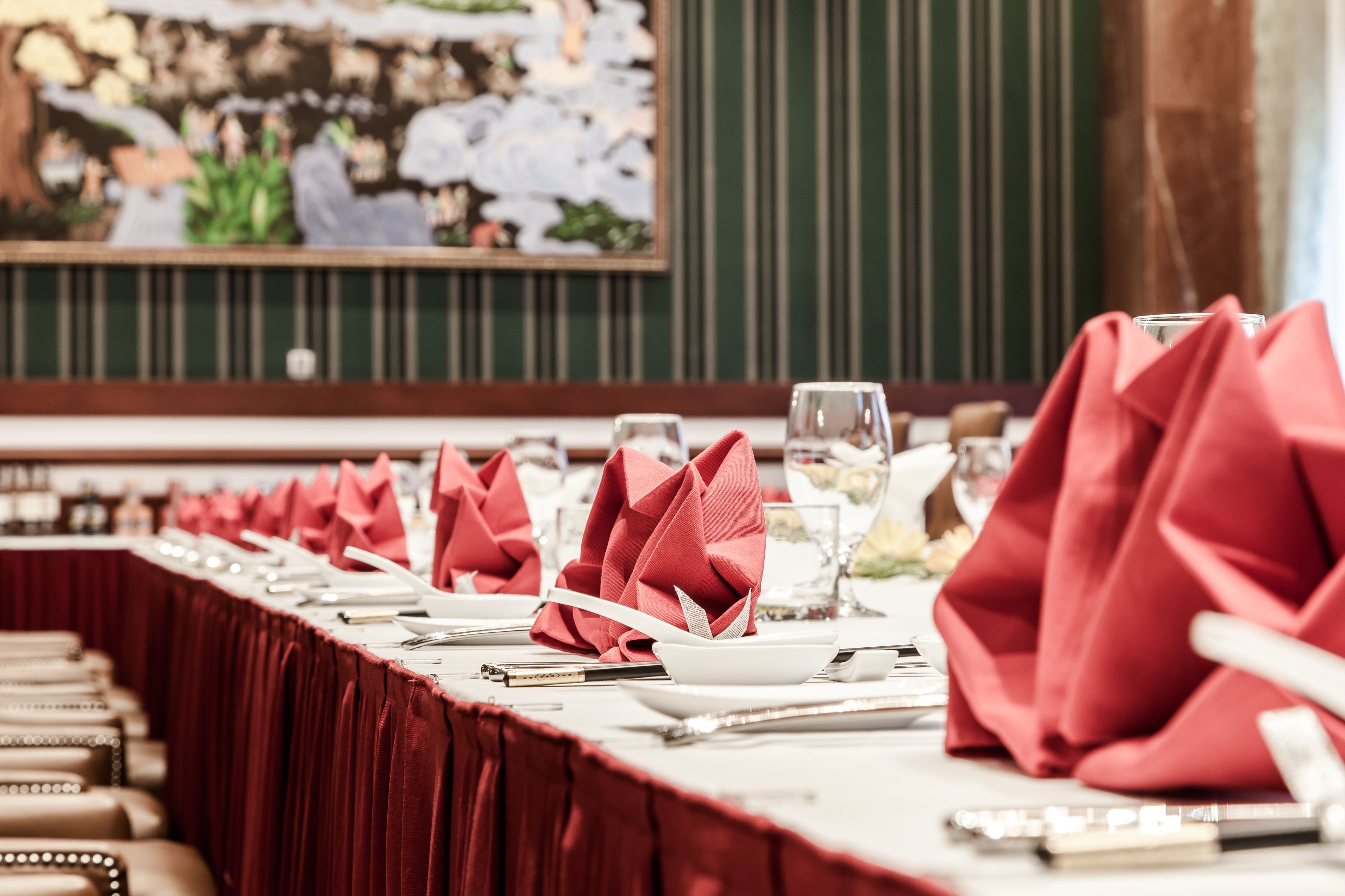 A dining table set with red napkins, white plates, and cutlery.