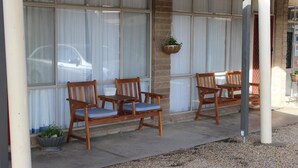 A building with a covered outdoor seating area featuring wooden chairs and a table. - Thomas Lodge Motel (Tocumwal)