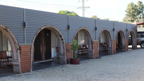 A building with multiple arched doorways and a gravel driveway. - Thomas Lodge Motel (Tocumwal)