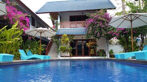 A swimming pool with blue water, surrounded by lounge chairs and umbrellas. - Marygio Resort (Gili Trawangan)