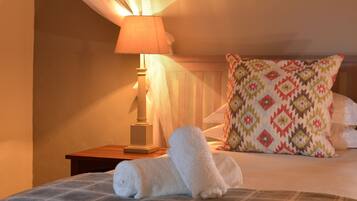 Una cama bien hecha con colcha escocesa, un cojín decorativo y una lámpara de noche.