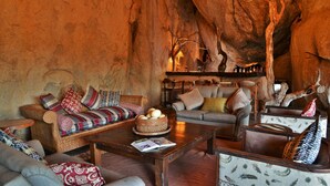 Un intérieur chaleureux avec une grande formation rocheuse, des meubles en bois et un lustre.