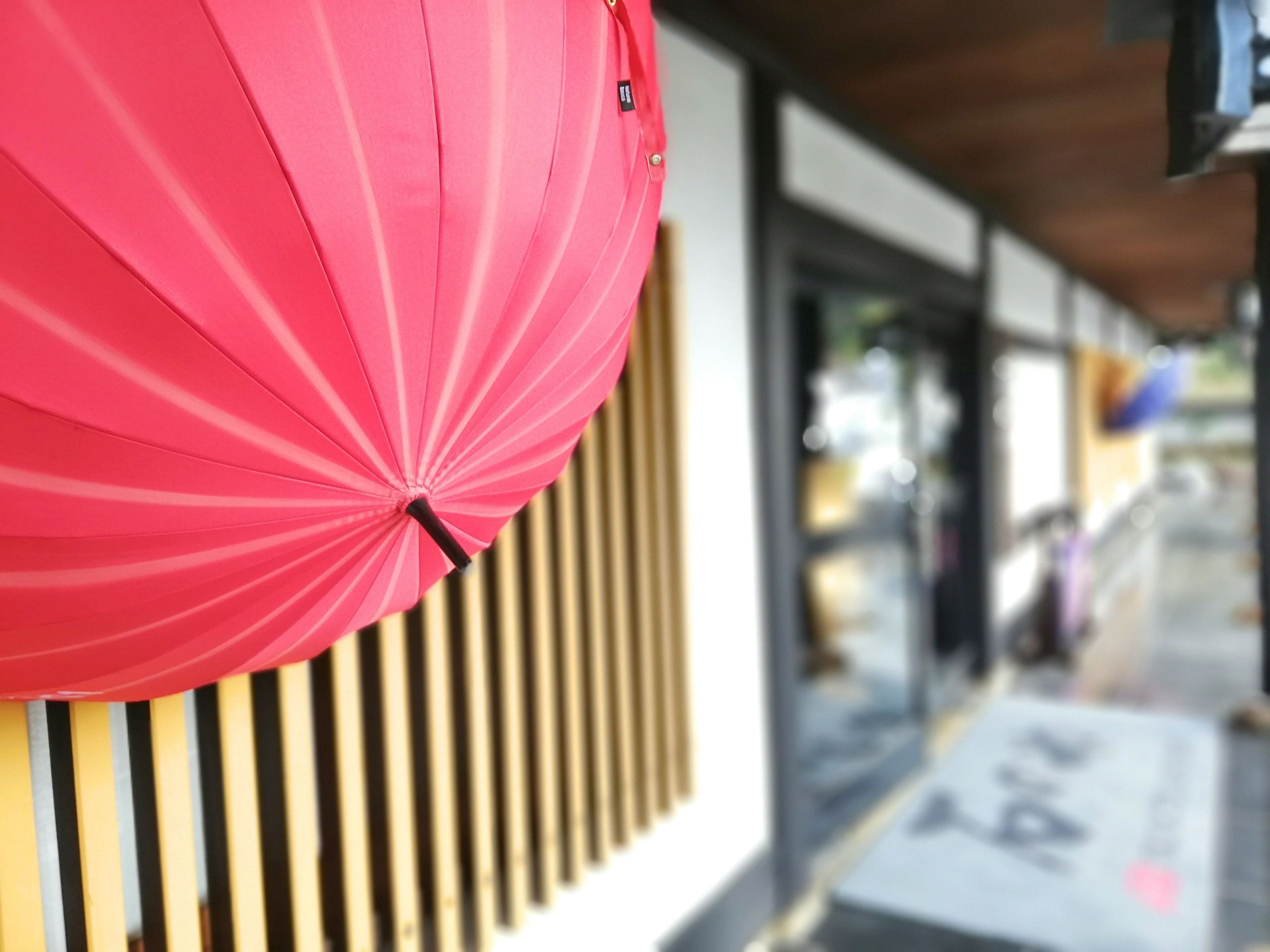 A red umbrella hanging on a building facade.