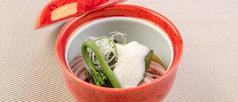 A bowl of food with a red lid on a woven mat.