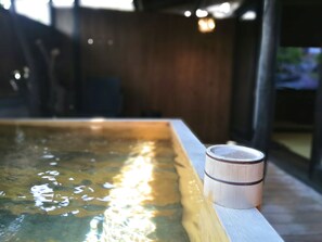 Une table en bois sur laquelle se trouve une tasse, placée à côté d’une piscine dont l’eau reflète la lumière du soleil.