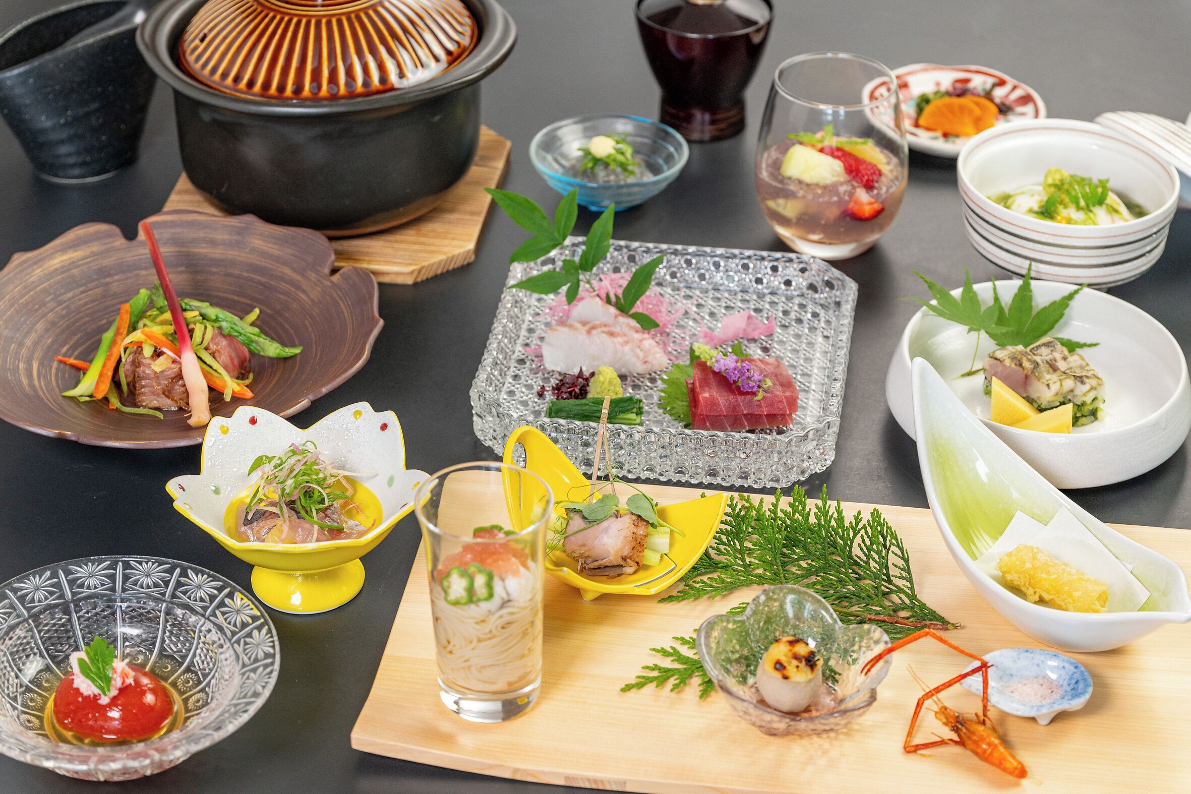 A variety of dishes and drinks on a table, including a pot, bowls, and glasses.