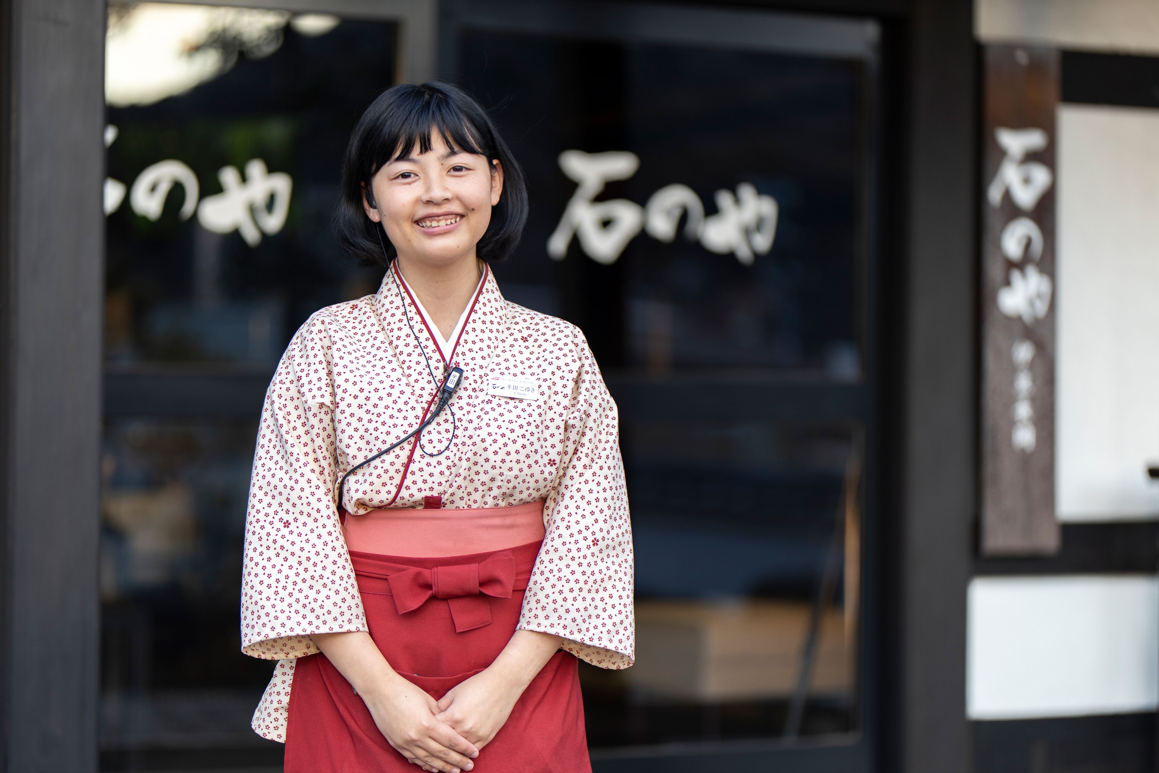 A person standing in front of a building with Japanese characters on the glass.