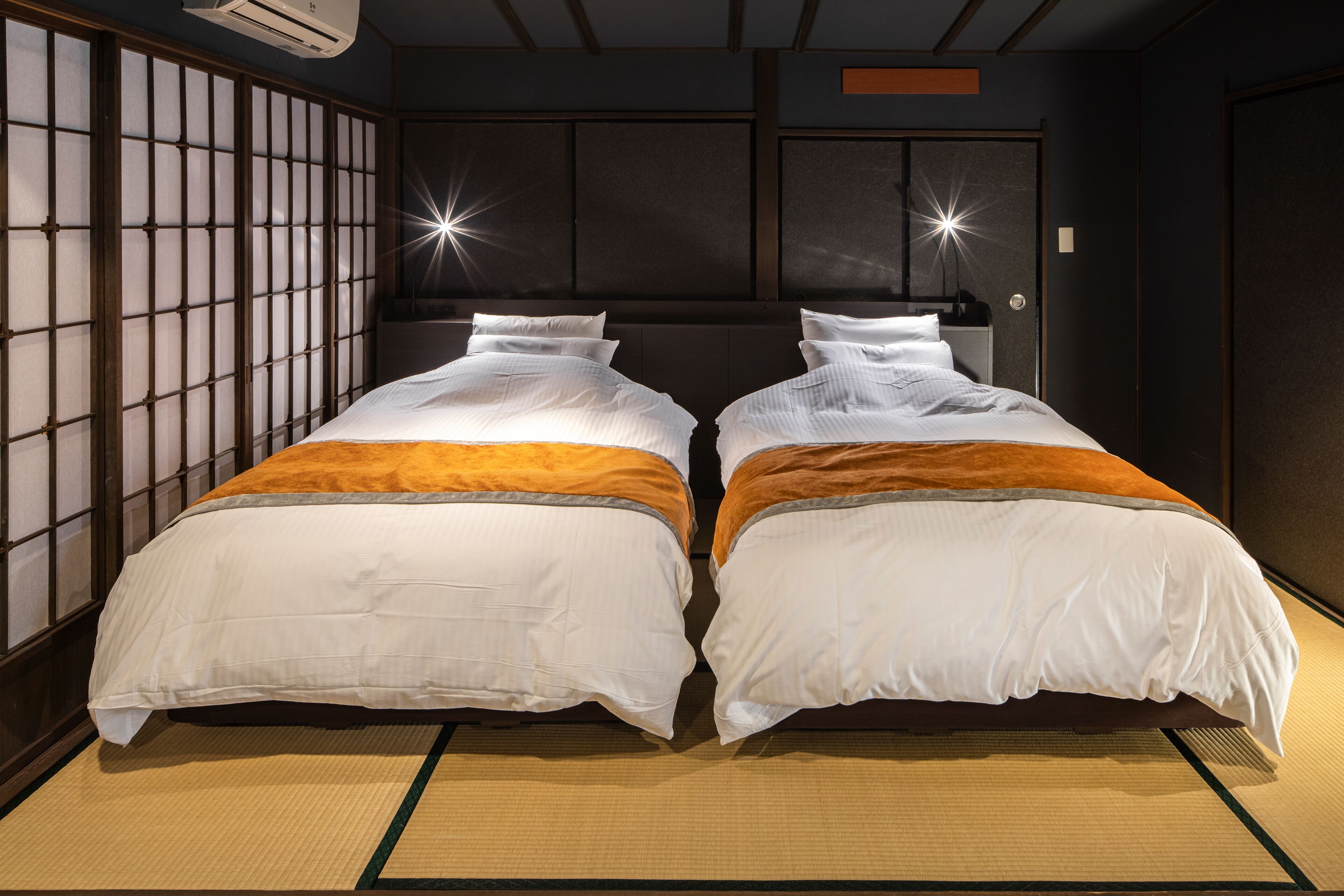Een kamer met twee bedden, een traditionele schuifdeur en een luchtkoeler aan het plafond.