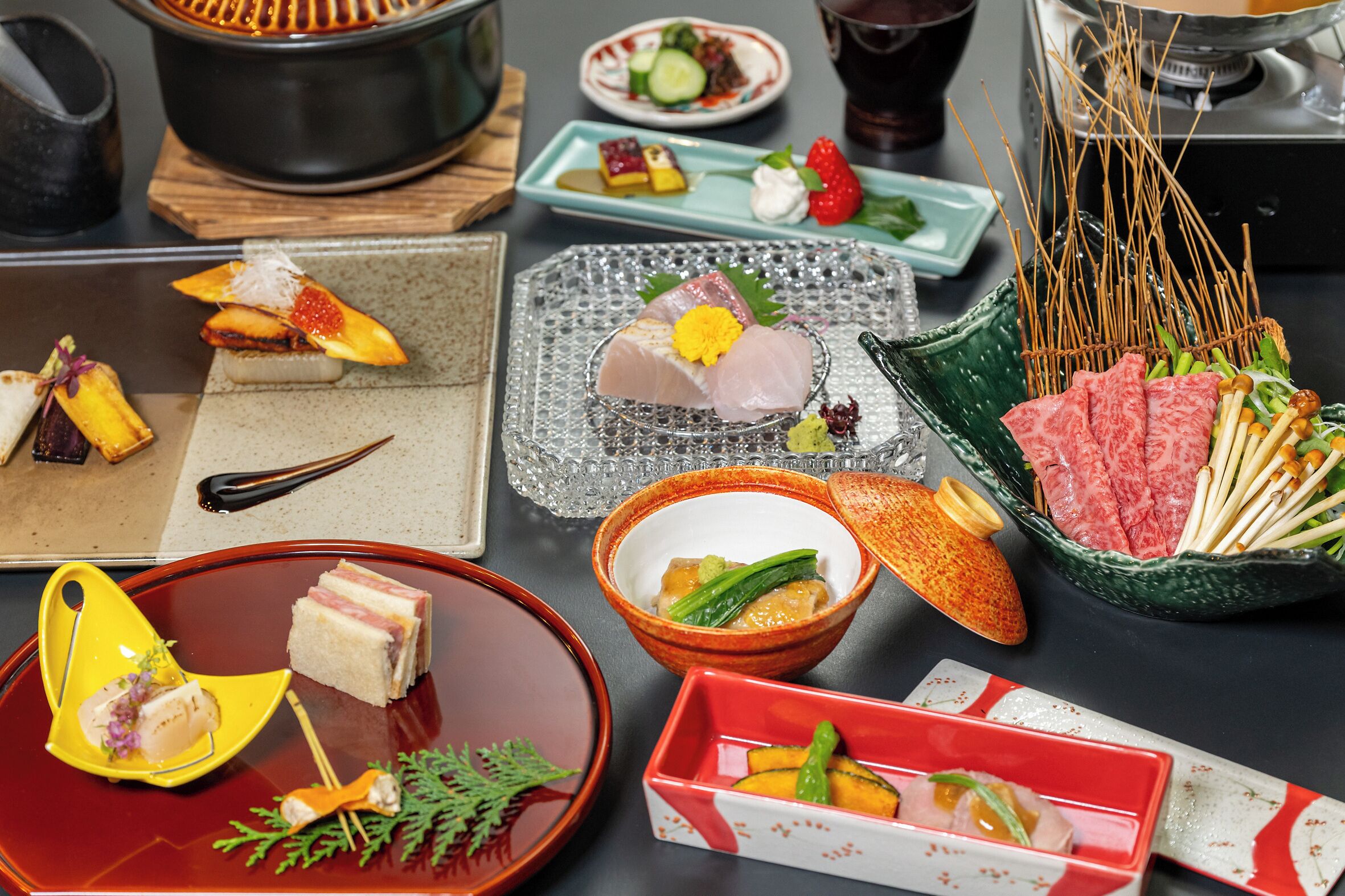 Une variété de plats et d’aliments sont présentés sur une table, notamment des sushis, des sashimis et d’autres amuse-gueules.