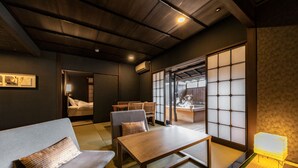 Una habitación japonesa tradicional con suelo de tatami, una mesa de madera baja, un sofá y puertas correderas shoji.