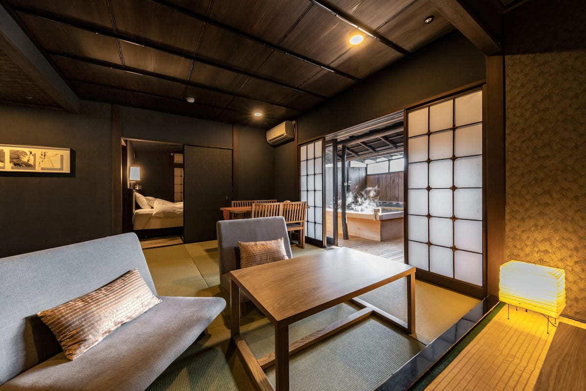 A traditional Japanese room with tatami flooring, a low wooden table, a sofa, and sliding shoji doors.