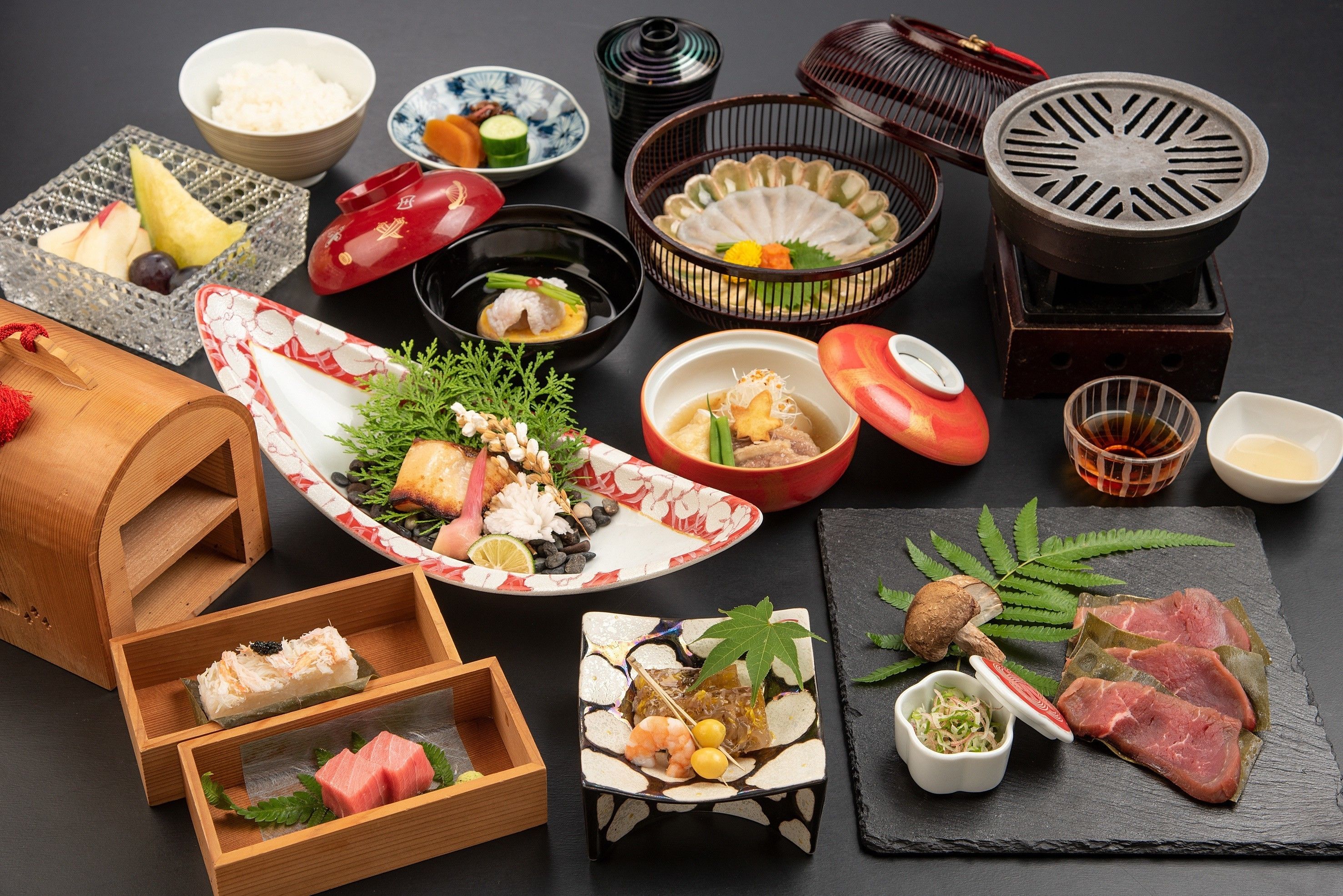 Variedad de platos japoneses, como sushi, sashimi y tempura, dispuestos sobre una mesa de pizarra negra.