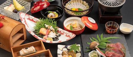 Variedad de platos japoneses, como sushi, sashimi y tempura, dispuestos sobre una mesa de pizarra negra.