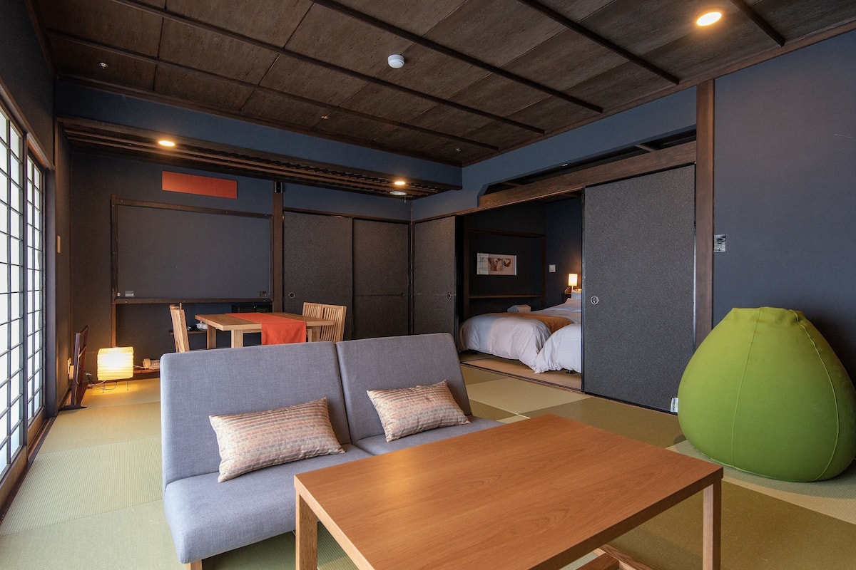 A modern hotel room with a sofa, a wooden table, and a green bean bag.